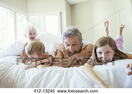 Stock Photography - Father and children relaxing on bed. Fotosearch