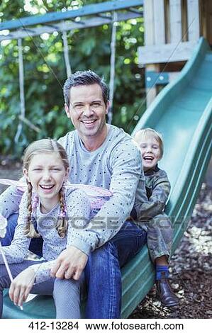 Father and children sitting on slide View Large Photo Image Picture - Father and children sitting on slide. Fotosearch
