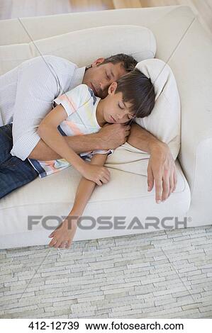 Stock Photo - Father and son napping on sofa in living room. Fotosearch
