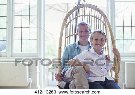 Father and son sitting in wicker chair View Large Photo Image Stock Image - Father and son sitting in wicker chair. Fotosearch