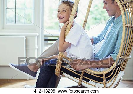 Stock Photograph - Father and son sitting in wicker chair. Fotosearch