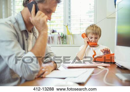 Father and son working in home office View Large Photo Image Stock Photo - Father and son working in home office. Fotosearch