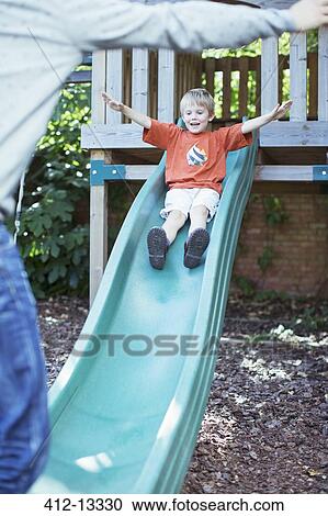 Stock Image - Father catching son on slide. Fotosearch