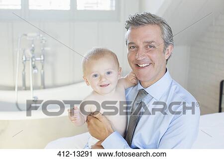 Stock Image - Father holding baby in bathroom. Fotosearch