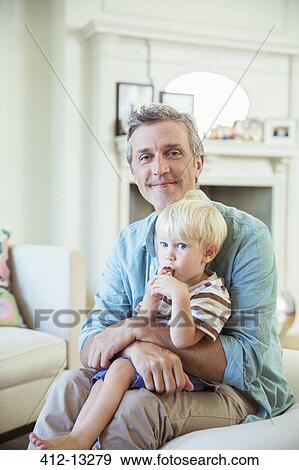 Stock Photo - Father holding son in living room. Fotosearch
