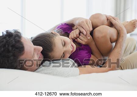 Stock Image - Father hugging daughter on bed. Fotosearch