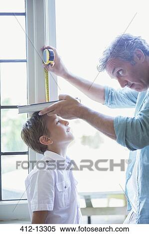Stock Photography - Father measuring son's height on wall. Fotosearch