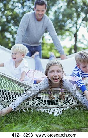 Stock Photo - Father pushing children in hammock outdoors. Fotosearch