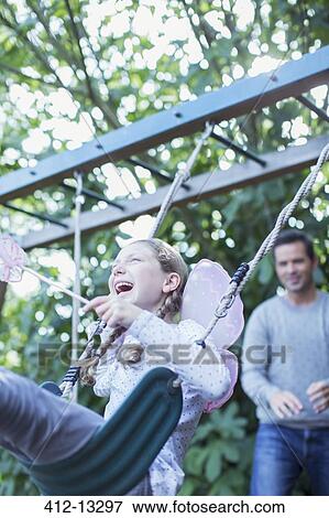 Father Pushing Daughter On Swing Outdoors Stock Photo