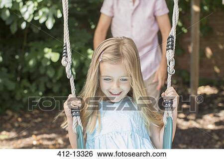 Stock Photograph - Father pushing daughter on swing. Fotosearch