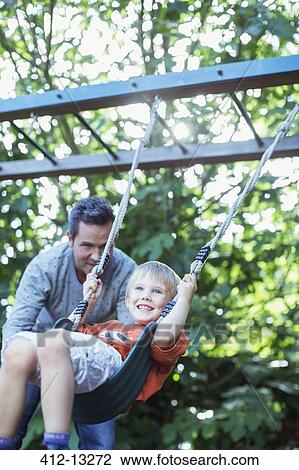 Father pushing son on swing outdoors View Large Photo Image Stock Image - Father pushing son on swing outdoors. Fotosearch