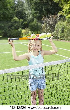 Stock Photograph - Girl holding tennis racket and balls on grass court. Fotosearch