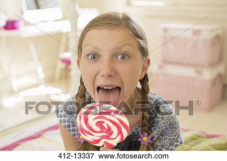Stock Photo - Girl licking lollipop in bedroom. Fotosearch