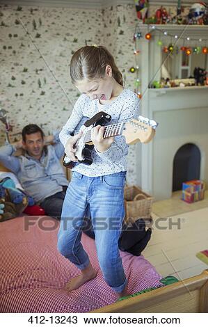 Girl playing guitar for father in bedroom View Large Photo Image Stock Image - Girl playing guitar for father in bedroom. Fotosearch
