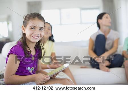 Girl using digital tablet on sofa in living room View Large Photo Image Stock Image - Girl using digital tablet on sofa in living room. Fotosearch