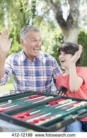 Stock Photo - Grandfather and grandson playing backgammon. Fotosearch