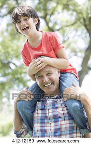 Grandfather carrying grandson on shoulders outdoors View Large Photo Image Stock Photo - Grandfather carrying grandson on shoulders outdoors. Fotosearch