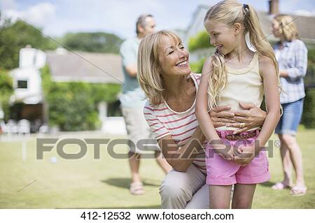 Stock Image - Grandmother hugging granddaughter outdoors. Fotosearch