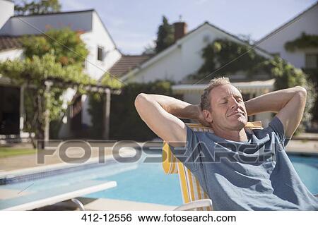 Stock Photograph - Man relaxing at poolside. Fotosearch