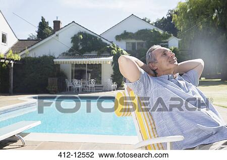 Man relaxing in lounge chair at poolside View Large Photo Image Stock Image - Man relaxing in lounge chair at poolside. Fotosearch