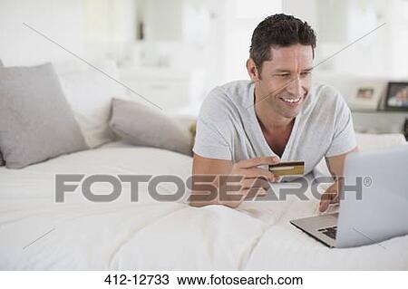 Man shopping online with laptop on bed View Large Photo Image Stock Image - Man shopping online with laptop on bed. Fotosearch