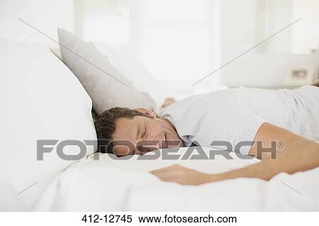 Stock Photography - Man sleeping on bed. Fotosearch