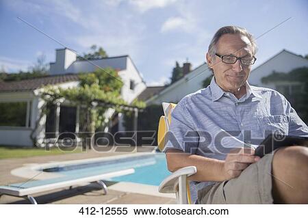 Man using digital tablet at poolside View Large Photo Image Stock Photography - Man using digital tablet at poolside. Fotosearch