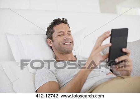 Man using digital tablet in bed View Large Photo Image Stock Image - Man using digital tablet in bed. Fotosearch