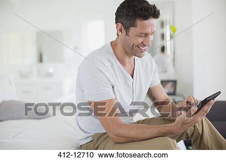 Man using digital tablet on bed View Large Photo Image Stock Image - Man using digital tablet on bed. Fotosearch