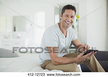Stock Image - Man using digital tablet on bed. Fotosearch