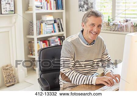 Man working at computer in home office View Large Photo Image Stock Image - Man working at computer in home office. Fotosearch