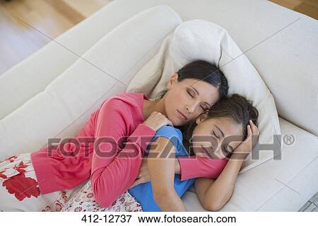 Mother and daughter napping on sofa in living room View Large Photo Image Stock Photo - Mother and daughter napping on sofa in living room. Fotosearch