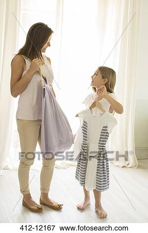 Stock Photo - Mother and daughter picking out clothes in bedroom. Fotosearch