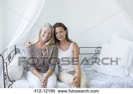 Stock Photography - Mother and daughter smiling on daybed. Fotosearch