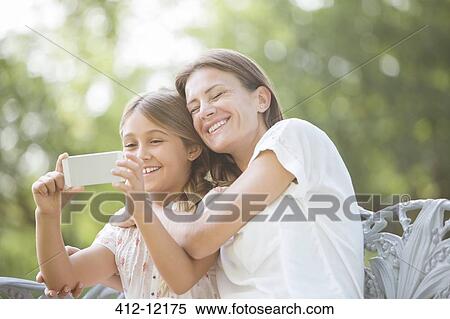 Mother and daughter using cell phone outdoors View Large Photo Image Stock Photography - Mother and daughter using cell phone outdoors. Fotosearch