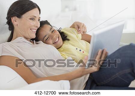Mother and daughter using digital tablet on sofa View Large Photo Image Stock Image - Mother and daughter using digital tablet on sofa. Fotosearch