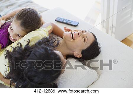 Mother and daughters laughing on sofa View Large Photo Image Stock Photography - Mother and daughters laughing on sofa. Fotosearch