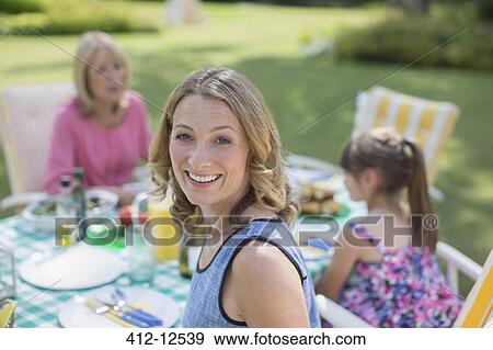 Multi-generation family eating at table in backyard View Large Photo Image Stock Photo - Multi-generation family eating at table in backyard. Fotosearch