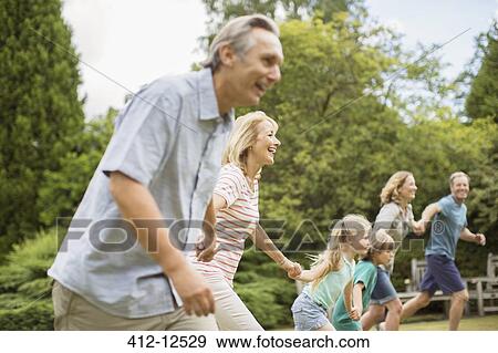 Multi-generation family holding hands and running View Large Photo Image Stock Photo - Multi-generation family holding hands and running. Fotosearch