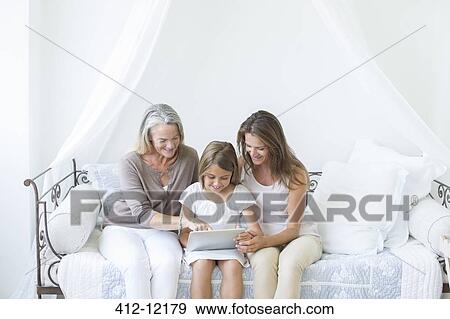 Multi-generation women using digital tablet on daybed View Large Photo Image Stock Photo - Multi-generation women using digital tablet on daybed. Fotosearch