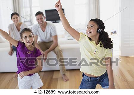 Stock Photo - Parents watching daughters dance in living room. Fotosearch