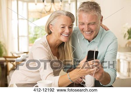 Senior couple sharing mp3 player in domestic kitchen View Large Photo Image Stock Image - Senior couple sharing mp3 player in domestic kitchen. Fotosearch