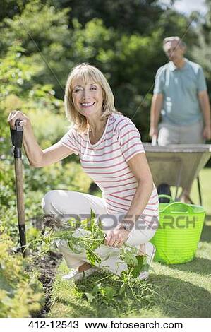 Stock Image - Senior couple working in garden. Fotosearch
