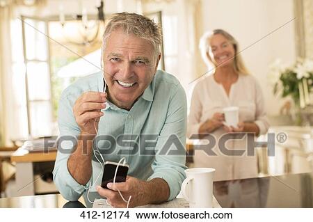 Senior man listening to mp3 player in kitchen View Large Photo Image Picture - Senior man listening to mp3 player in kitchen. Fotosearch