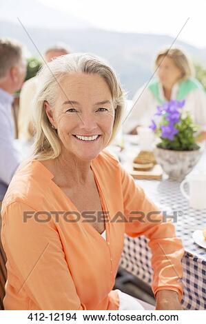 Picture - Senior woman smiling at patio table. Fotosearch