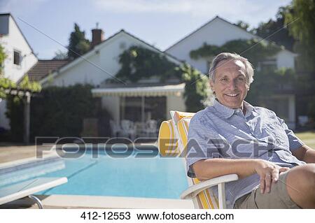 Smiling man in lounge chair at poolside View Large Photo Image Stock Image - Smiling man in lounge chair at poolside. Fotosearch