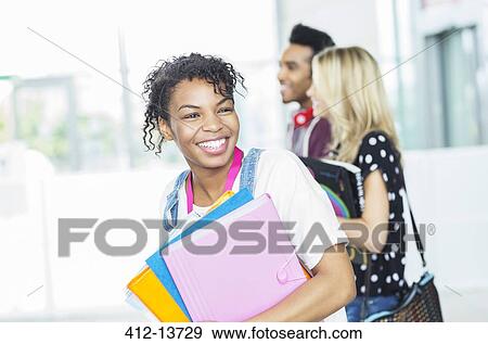 Smiling university student carrying folders View Large Photo Image Stock Photo - Smiling university student carrying folders. Fotosearch