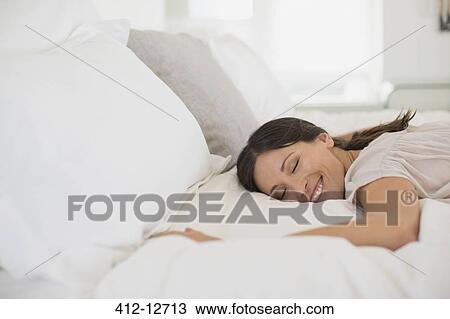 Smiling woman laying on bed View Large Photo Image Stock Image - Smiling woman laying on bed. Fotosearch