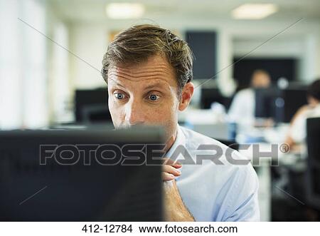 Picture - Surprised businessman at computer in office. Fotosearch
