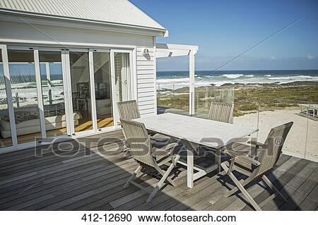 Table and chairs on balcony overlooking beach View Large Photo Image Stock Image - Table and chairs on balcony overlooking beach. Fotosearch